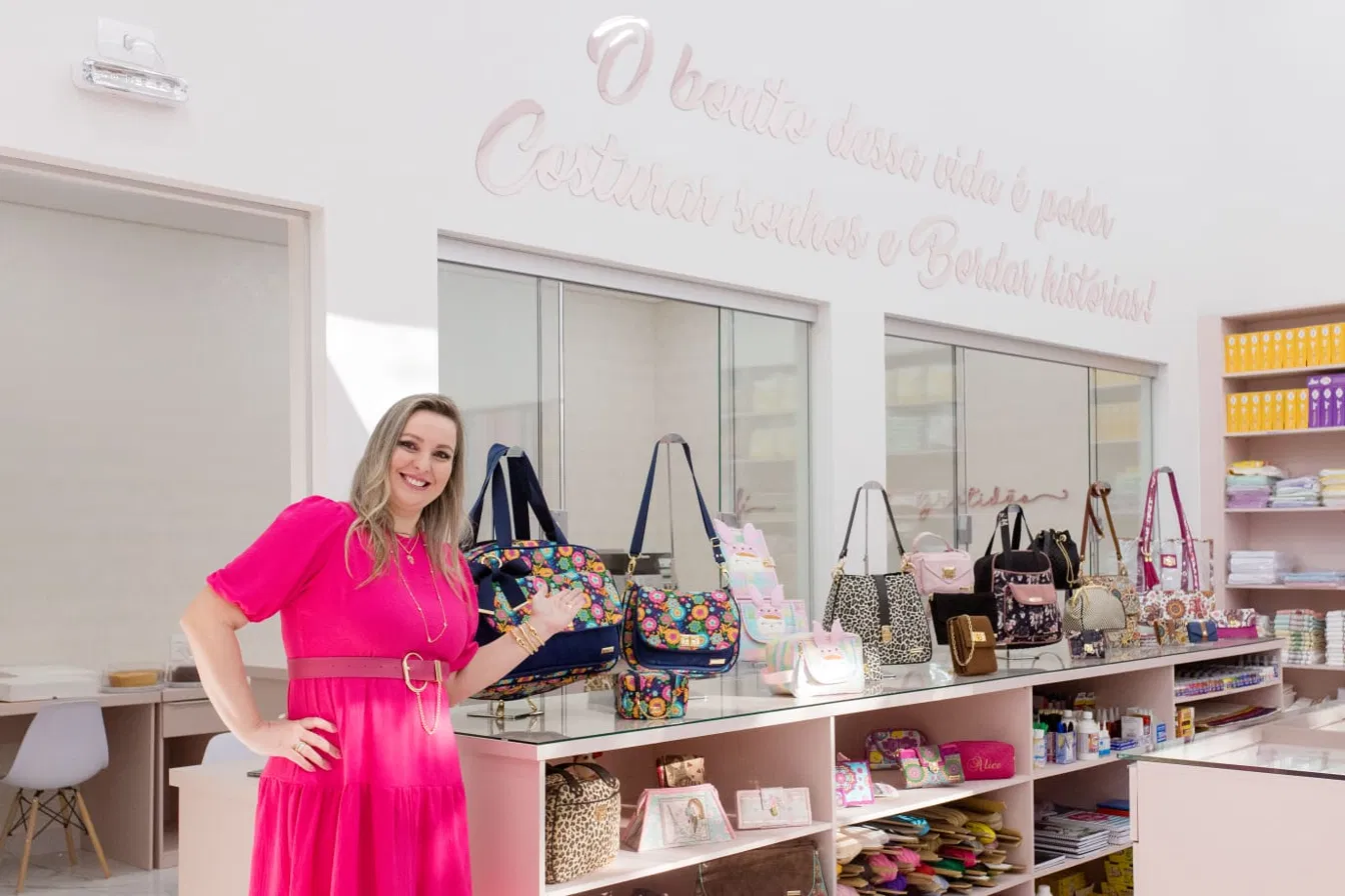 Proprietária ao lado da vitrine de bolsas na Villa Artesanato